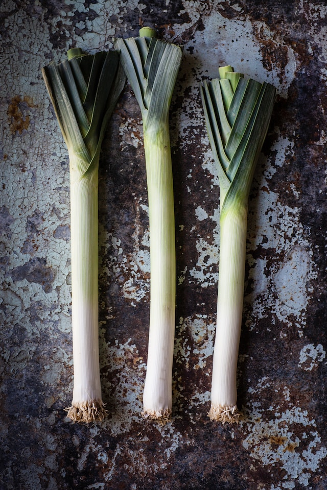 3 poireaux allignés sur une table